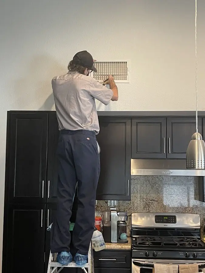 Technician inspecting an air vent during HVAC service in Morrisville